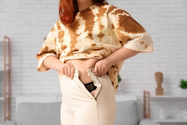 Image of woman trying to do her trousers up after pregnancy weight gain Wraysbury