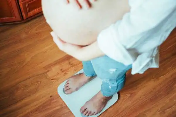 Image of woman weighing herself and experiencing weight gain through pregnancy Wraysbury